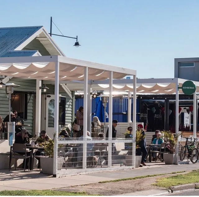 Outdoor café with patrons dining under white canopies.