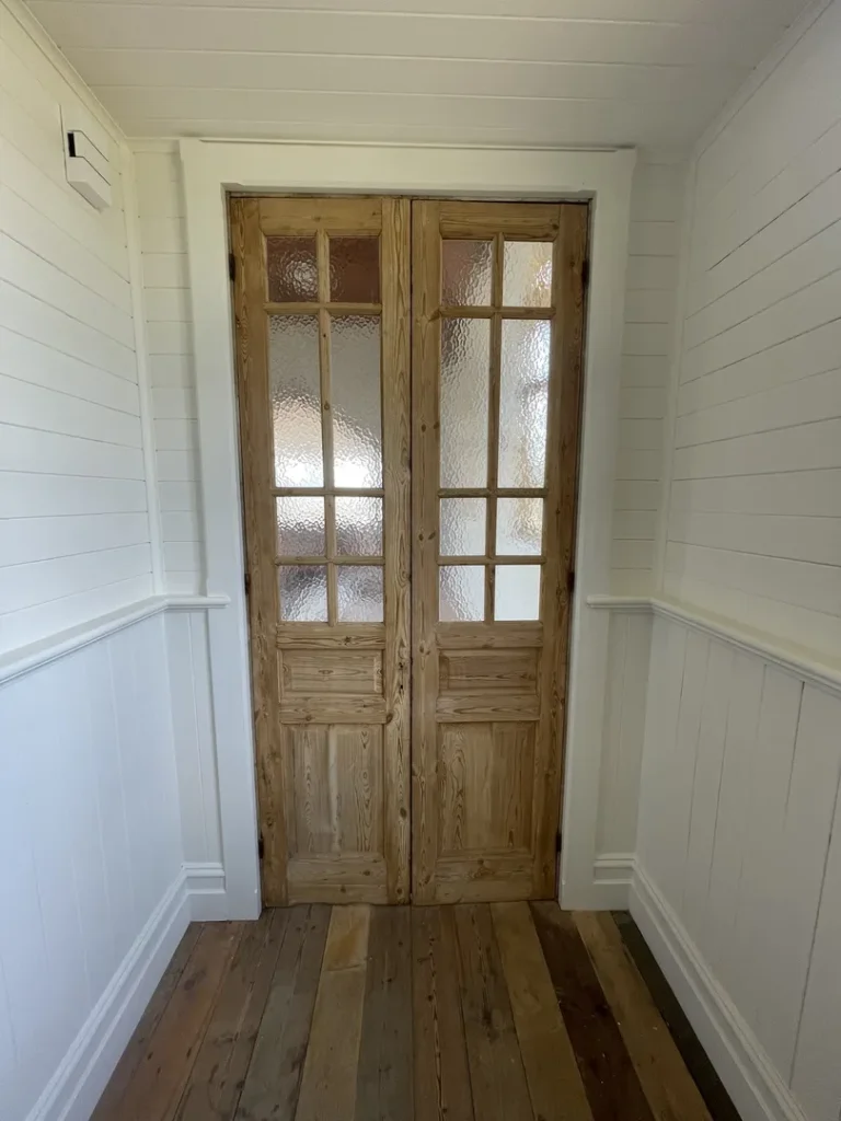 Wooden double doors with textured glass panels in hallway.