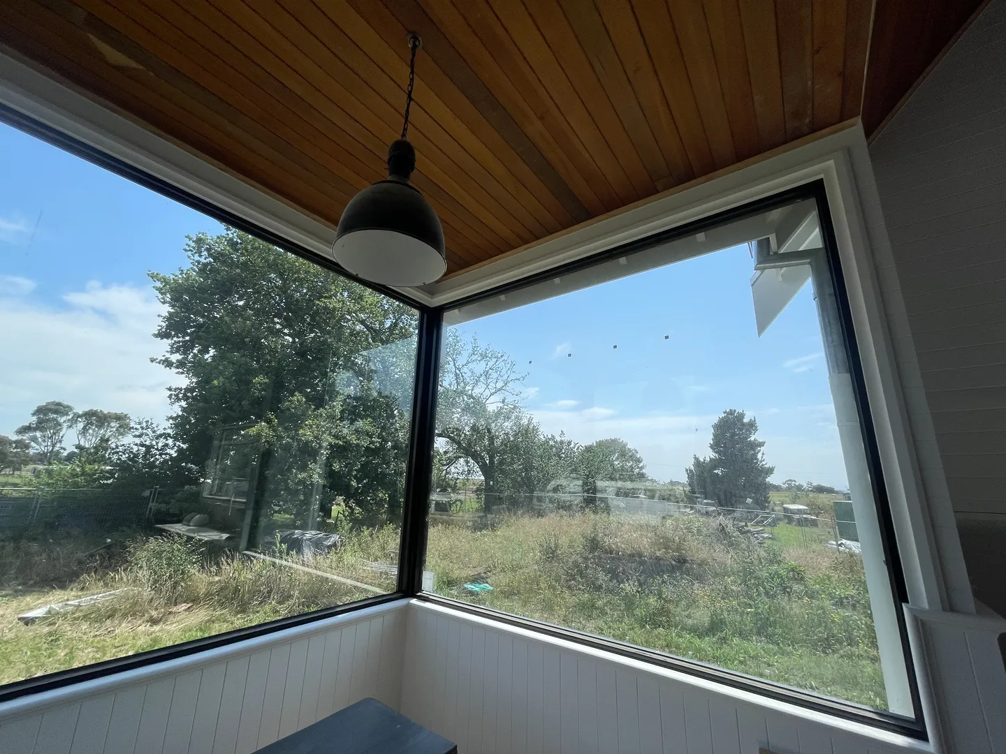 Bright sunlit room with large window overlooking countryside.