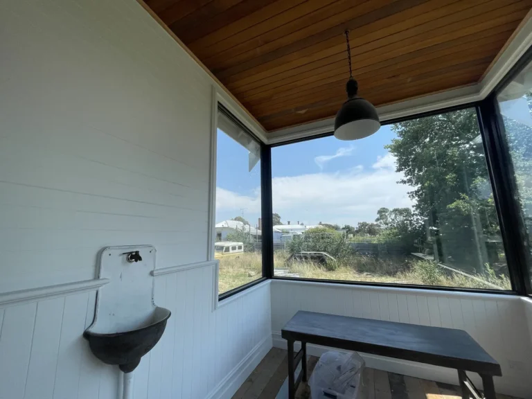 Bright sunroom with table, pendant lamp, and vintage sink.