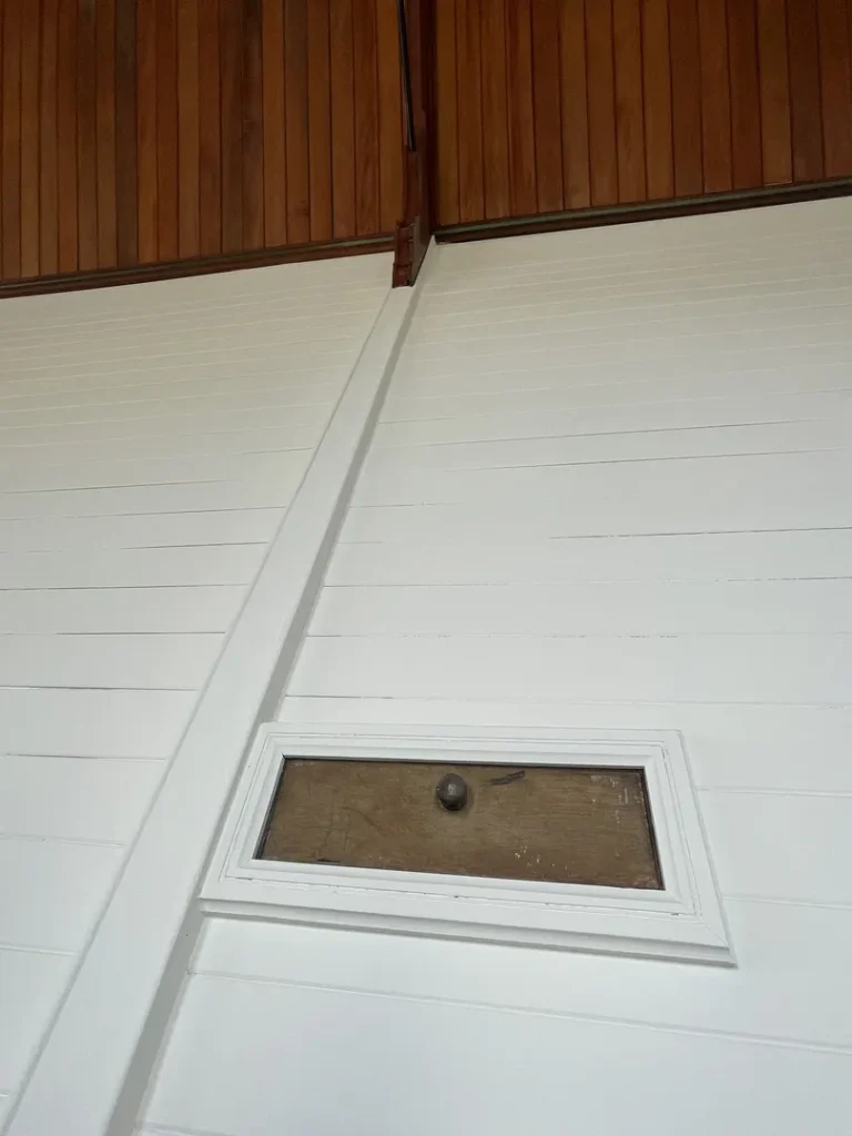 White wall with small rectangular window and wooden details.