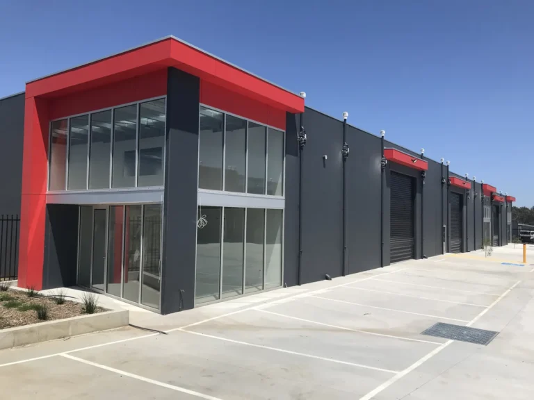 Modern red and gray commercial building with parking.