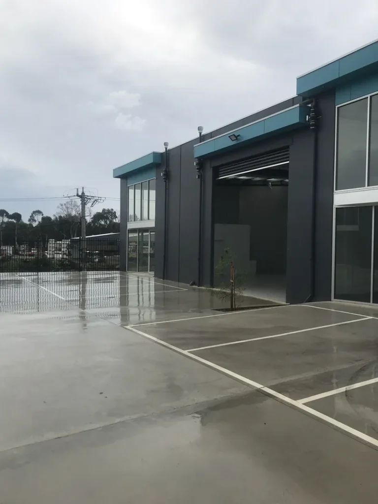 Modern industrial building with parking lot on cloudy day.