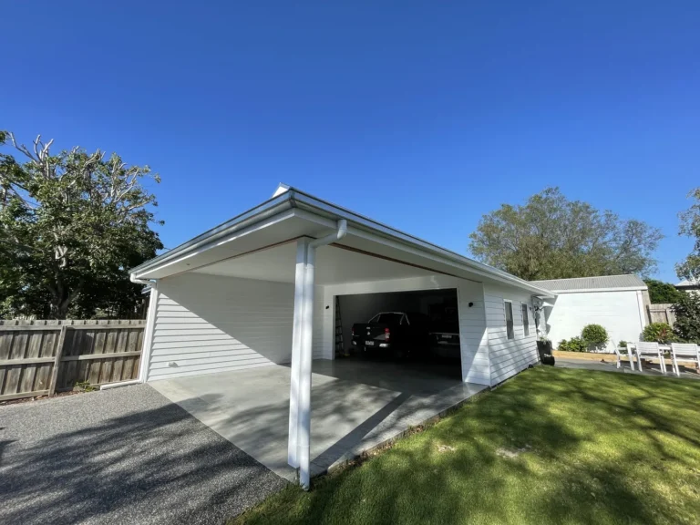 White carport attached to house, sunny day with clear sky.