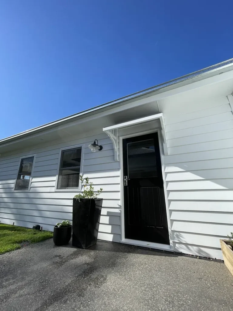 White siding house entrance with potted plants.